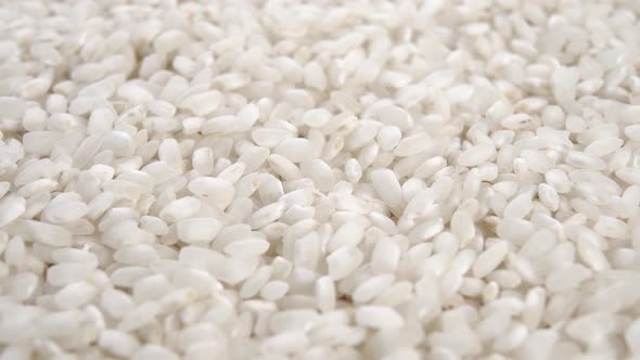 Uncooked white rice falling on a pile in slow motion. Macro