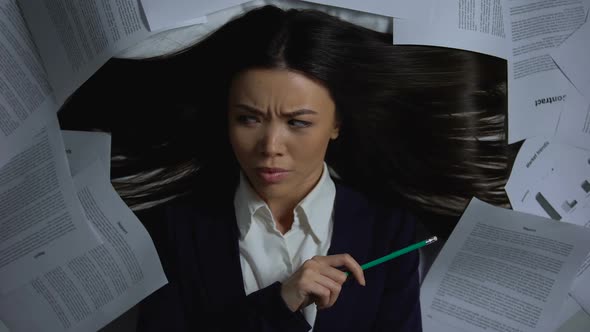 Female Asian Businesswoman Overwhelmed With Paperwork, Lack of Productivity