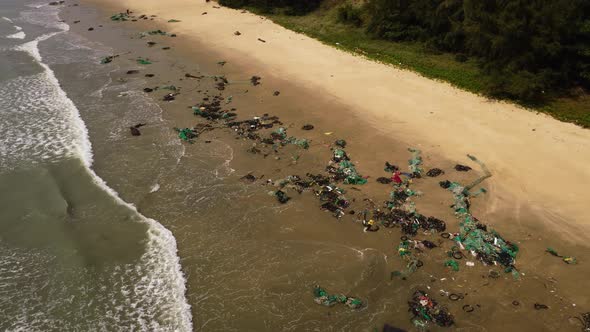 Aerial top down shot of dirt and waste at sandy beach after Typhoon Rai - orbit shot