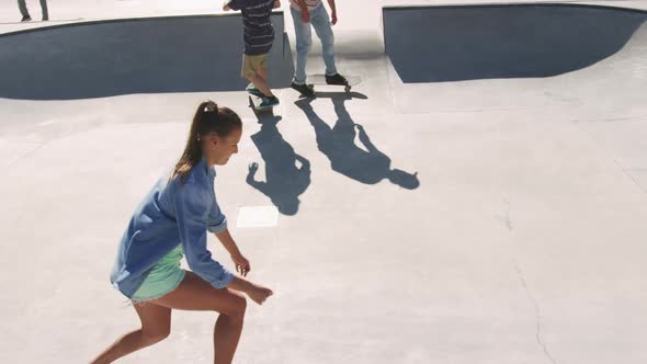 Caucasian woman and two male friends skateboarding on sunny day