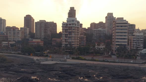 Flying alongside a costal city at sunrise with the sun peaking out behind the buildings short