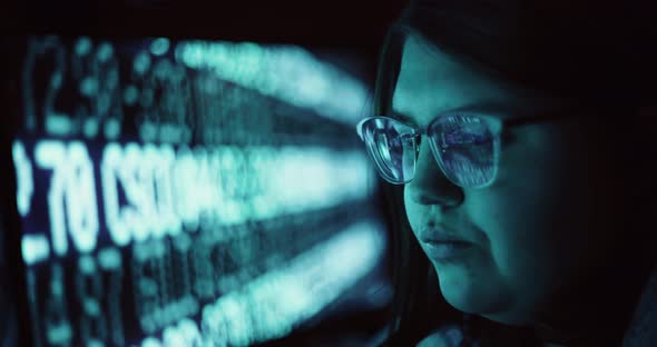 Closeup of Young Adult Female Wearing Reflective Glasses Analyzing Cyber Security Data Code Working