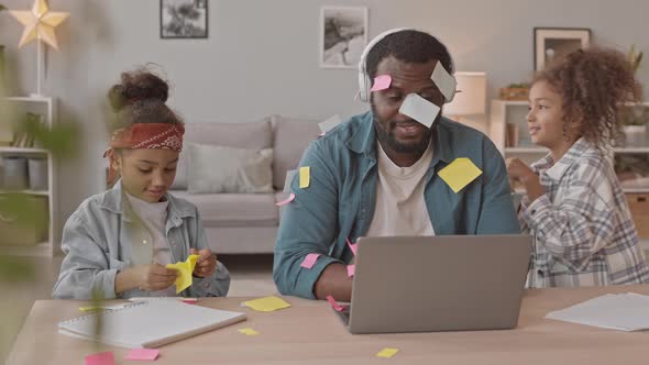Daughters Putting Sticky Notes on Their Father