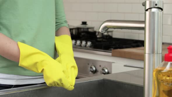 Woman finishing washing up and removing rubber gloves