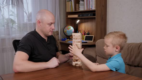 Father and Son Play Together a Board Game with Wooden Blocks Sitting at Home