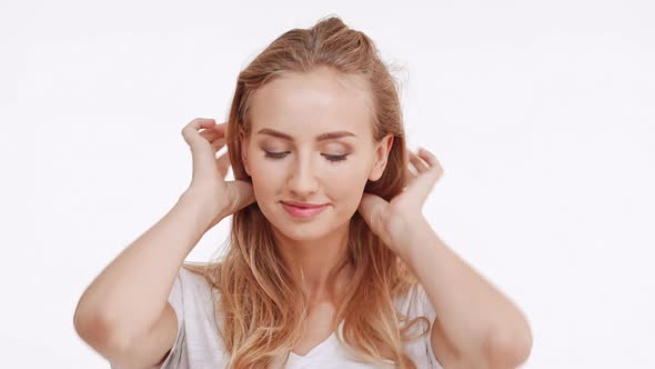 Young Beautiful Caucasian Blonde Girl Smiling Touching Hair Flirting on White Background in