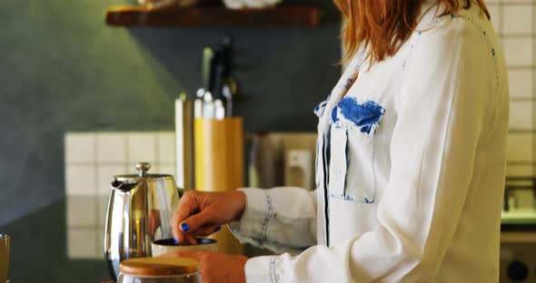 Woman stirring coffee in kitchen 