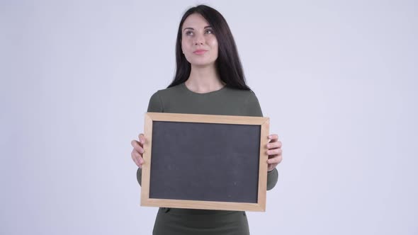 Happy Young Beautiful Woman Thinking While Holding Blackboard