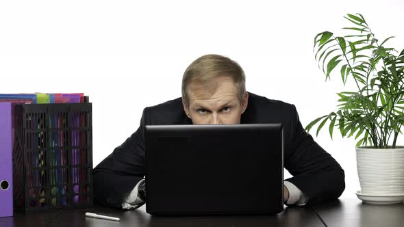 Businessman Manager Hides Behind a Laptop and Looks Out While Working in Office
