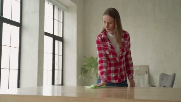 Young Woman Wipes a Table with a Rag at Home