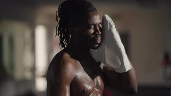 Side View Exhausted Handsome African American Sportsman Wiping Sweat with Towel Exhaling