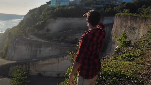 Young Male Traveler Enjoying Beautiful Sunset While Standing on a Rock on a Background of the Sea