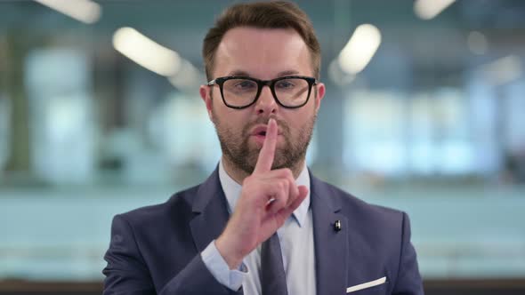 Middle Aged Businessman Showing Quiet Sign Finger on Lips
