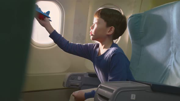 Asian young little boy wants to be a pilot, playing aircraft model toy while sitting on airplane.