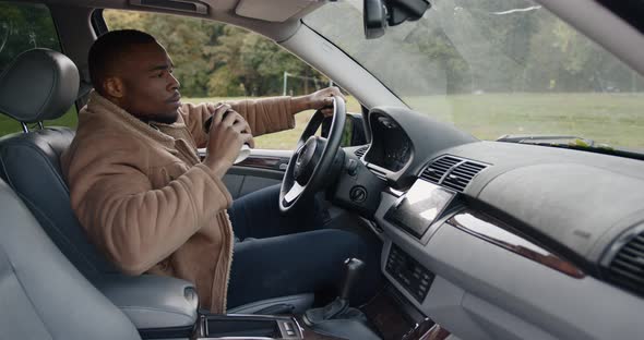 Young Man Drinking Coffee in the Car