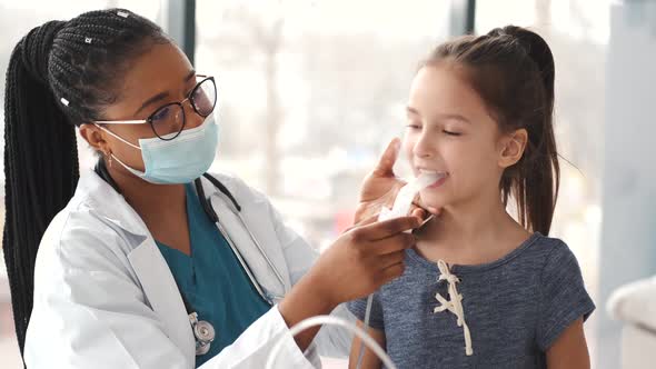 African Woman Doctor Holds a Mask Vapor Inhaler for Little Girl