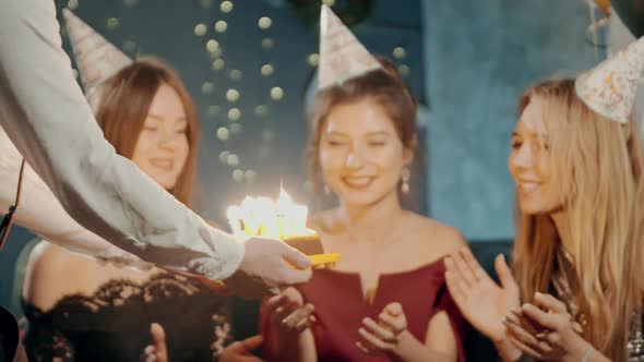 Young Woman Blowing Out Fire on Candles and Making Wish at Party or Celebration