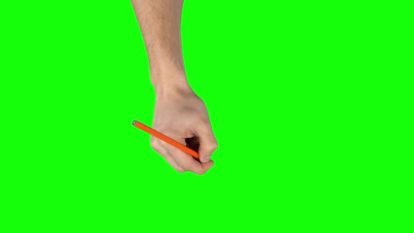 Male Hand with Orange Pencil Is Writing on Green Screen Background