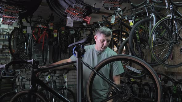 Service Engineer Performs Diagnostics and Repairs of Bicycle in Professional Workshop