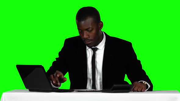 Businessman Uses the Calculator and a Laptop. Green Screen