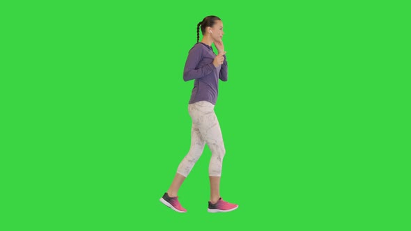 Female Runner Athlete Running and Listening Music in Wireless Ear Buds on a Green Screen Chroma Key