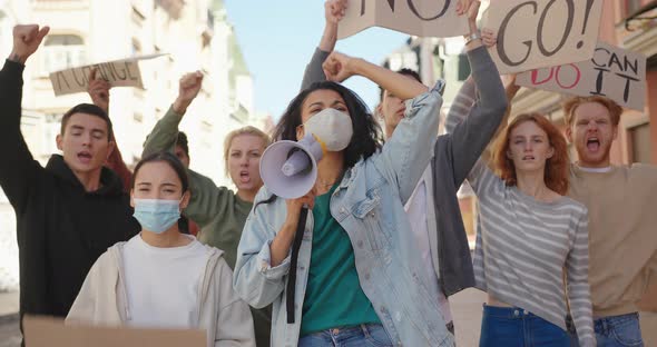 Mixed Race Protester Woman in Medical Mask Shouts Slogans Into Megaphone at Protest