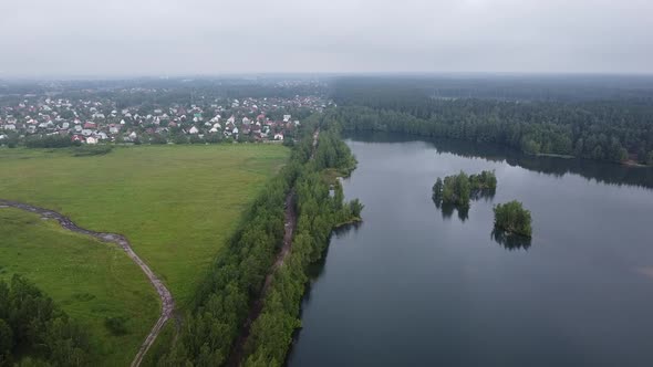 Drone - Flying over lake with forest and village