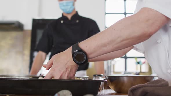 Caucasian female chef teaching diverse group wearing face masks