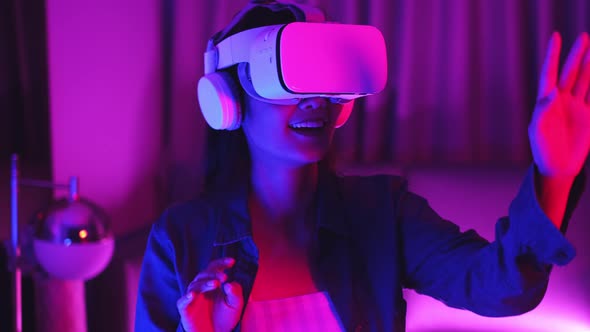 Young asian woman is using virtual reality headset. Neon light studio portrait.