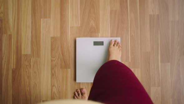 Legs of losing weight woman stand on scales and numbers, her weight, and top view shown on scales