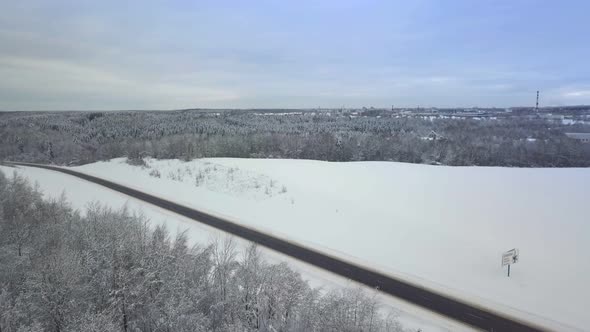 Drone. Coniferous forest, road and village. Asphalt. Winter landscape.