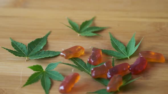 Slow Motion CBD Gummies Falling Onto Marijuana Leaves