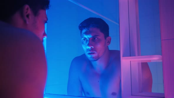 Tired Man with Stubble on His Face Washes in Bathroom and Look Himself in Mirror