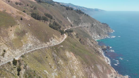 Drone follows cars driving on the ragged coastline of Big Sur Highway 1