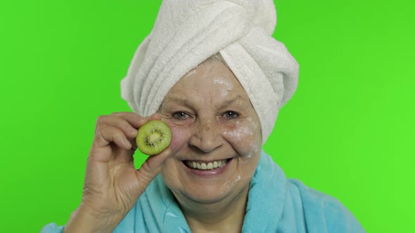 Elderly Grandmother in Bathrobe. Old Woman with Half of Kiwi in Her Hand