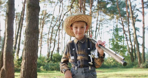 Small Angler in Straw Hat which Looking at Camera with Fishing Rods Among Green Trees