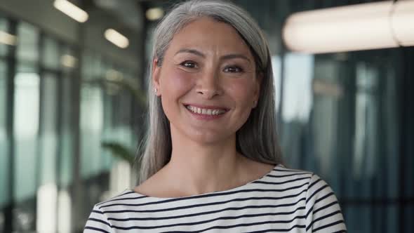 Happy adorable grey haired businesswoman smiling cheery, while posing in co-working interior