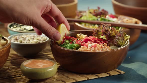 Squeezing Lemon Juice on Poke Bowl Closeup