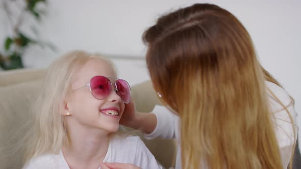 Happy Little Girl and her Mother Trying on Sunglasses