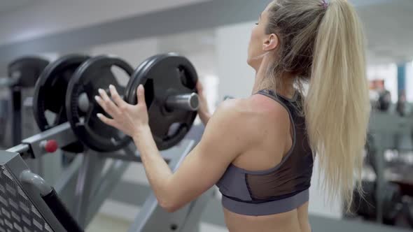 Beautiful muscular girl is getting ready to perform a barbell exercise