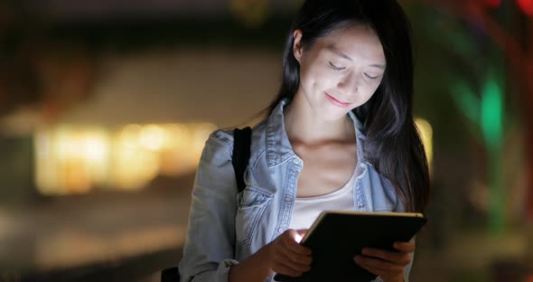 Woman looking on tablet computer at night