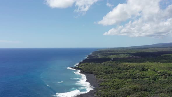 Wide aerial panning shot of a newly formed black sand beach on the Big Island of Hawaii. 4K