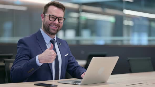 Middle Aged Businessman Using Laptop with Thumbs Up Sign