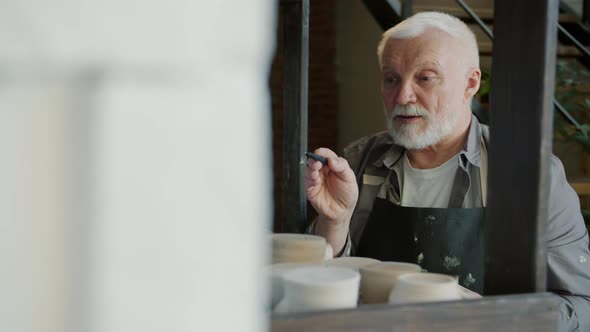 Slow Motion of Senior Ceramist Counting Pots and Vases in Workshop Writing Info