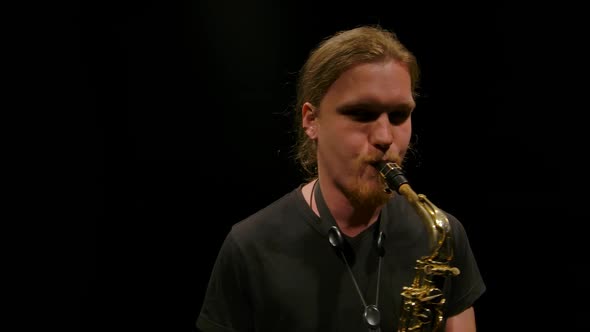 Camera Rotates Around a Young Man Playing the Saxophone