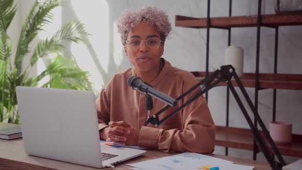 Cheerful African Woman Recording Podcast From Home with Laptop and Microphone