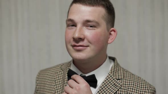 Handsome Groom in a Jacket and Bowtie Smiling and Looking at Camera. Wedding Morning