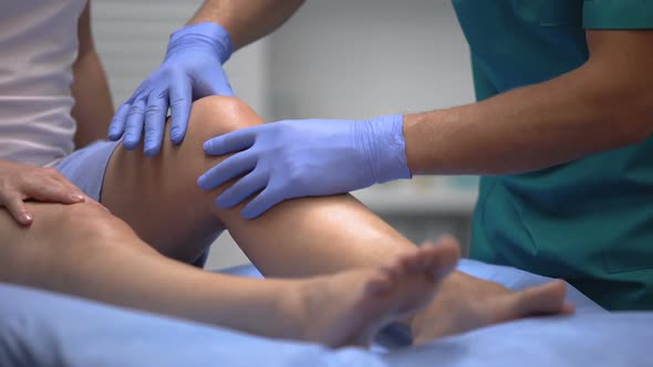 Doctor in Gloves Examining Painful Knee of Female Patient Leg Trauma, Healthcare