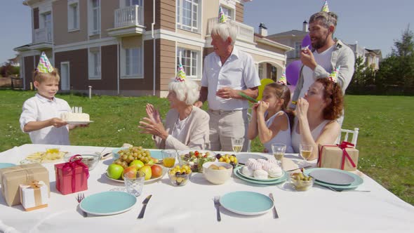 Little Boy Bringing Birthday Cake to Grandmother on Family Dinner