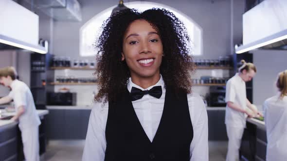 African American female restaurant manager in the kitchen, looking at camera, smiling